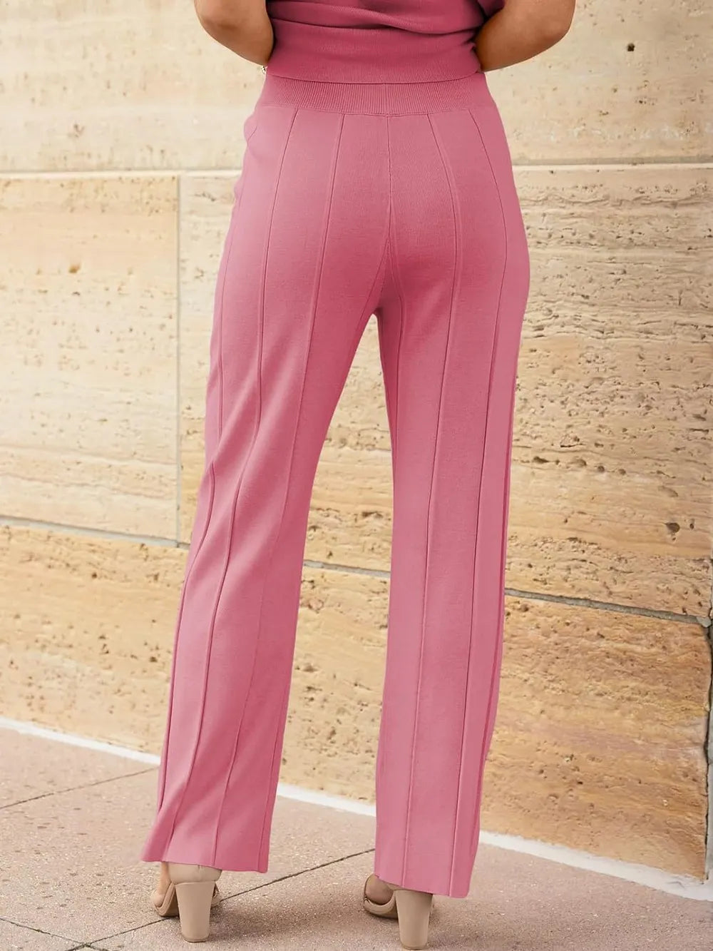 Pink pants worn by a person against a stone wall background