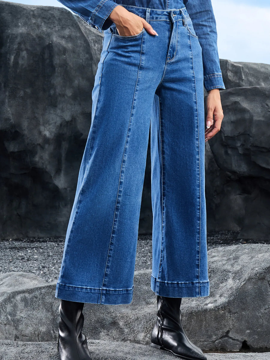 Person wearing blue jeans standing against a rocky background