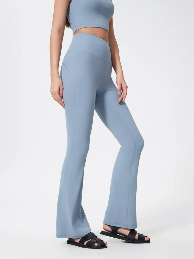 Person wearing light blue flared pants and a matching top on a white background