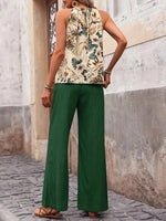 Person wearing a floral top and green pants on a stone pavement.