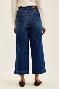 Person wearing blue jeans on a plain background