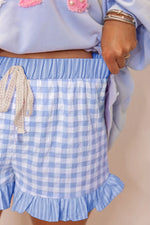 Light blue checkered shorts with ruffle details on a plain background