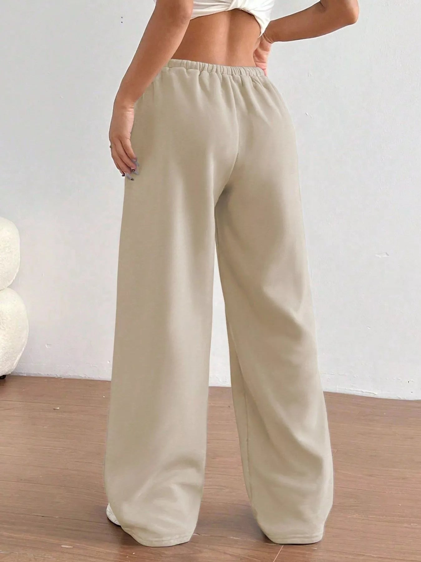Beige wide-leg pants worn by a person on a light wooden floor.