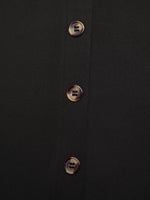 Close-up of a black shirt with gold buttons on a dark background