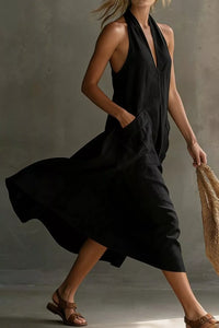 Woman wearing a black halter neck dress against a neutral background
