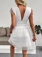 Woman wearing a white dress with a backless design in an indoor setting.