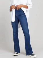Person wearing blue jeans and a white shirt on a plain background