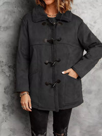 Person wearing a black duffel coat against a gray background