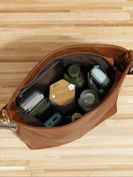 Brown leather bag with compartments on a wooden surface