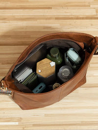 Brown leather bag with compartments on a wooden surface