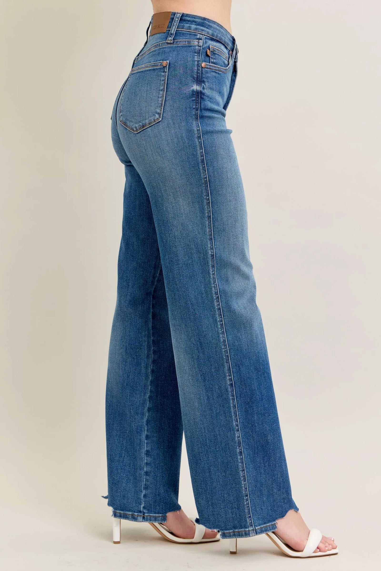 Blue jeans worn by a person on a plain background