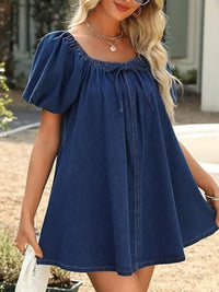 Woman wearing a blue dress with puff sleeves outdoors.