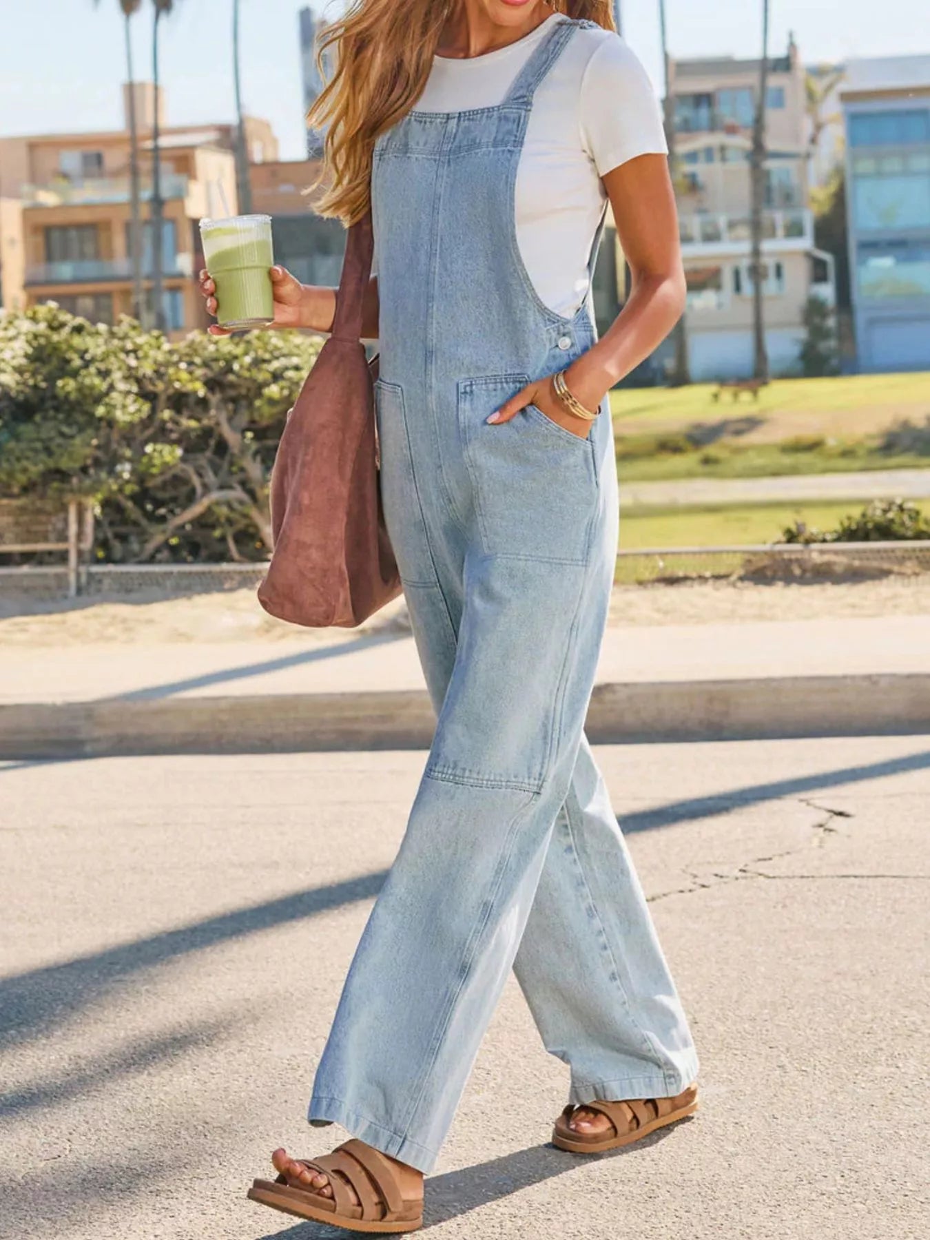 Person wearing light blue denim overalls with a blurred outdoor background