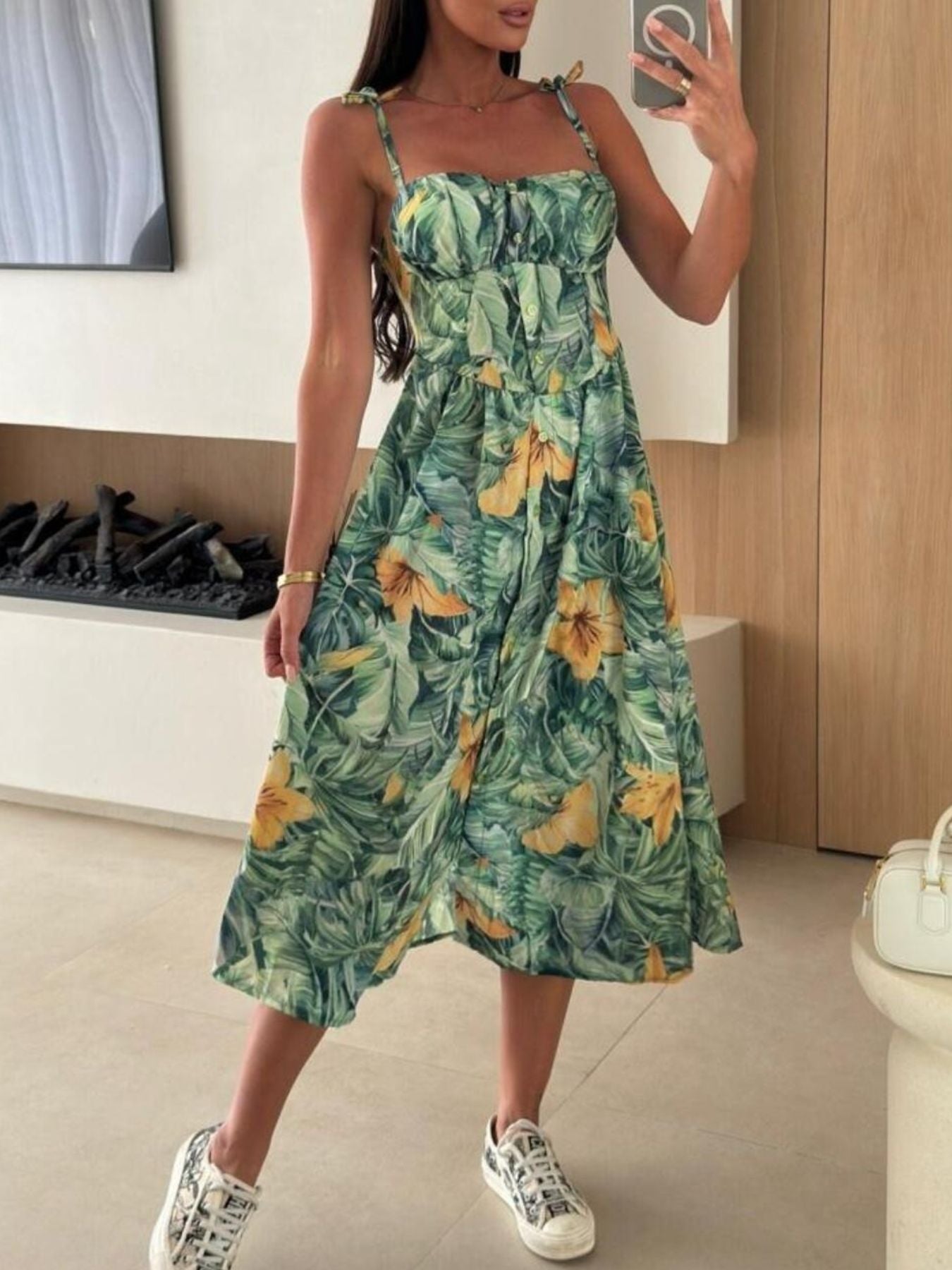 Woman wearing a green floral dress in a room with a television and cabinet.