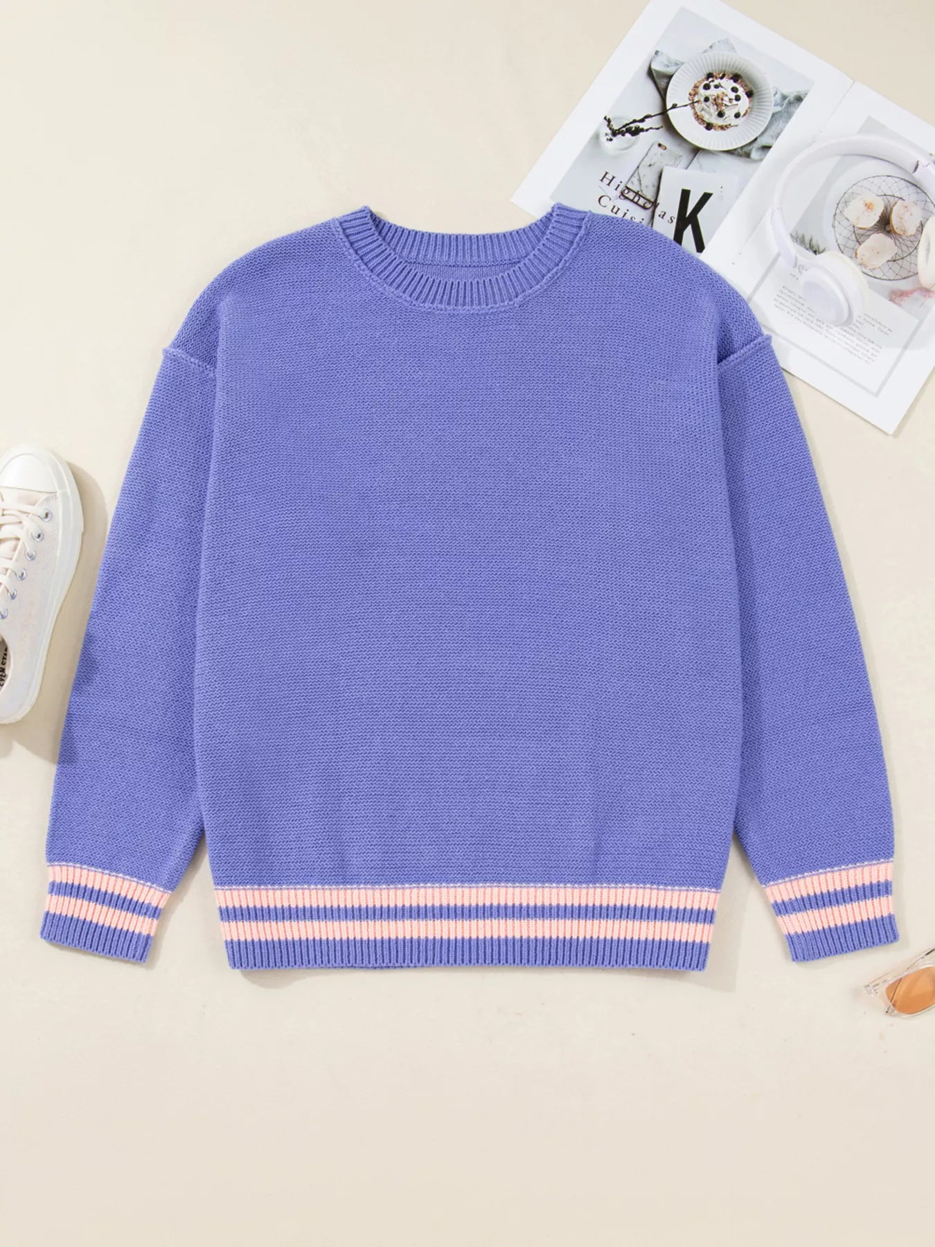 Blue sweater with striped cuffs on a beige surface