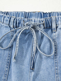 Close-up of blue denim shorts with drawstring on a white background