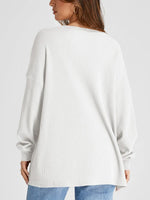 White ribbed sweater worn by a person on a light gray background