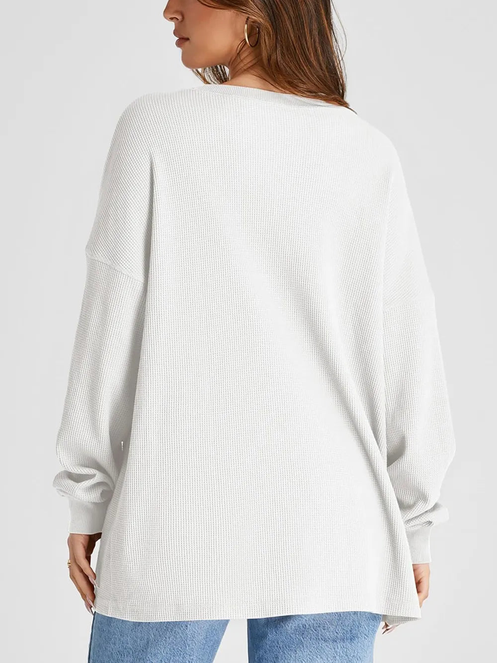 White ribbed sweater worn by a person on a light gray background