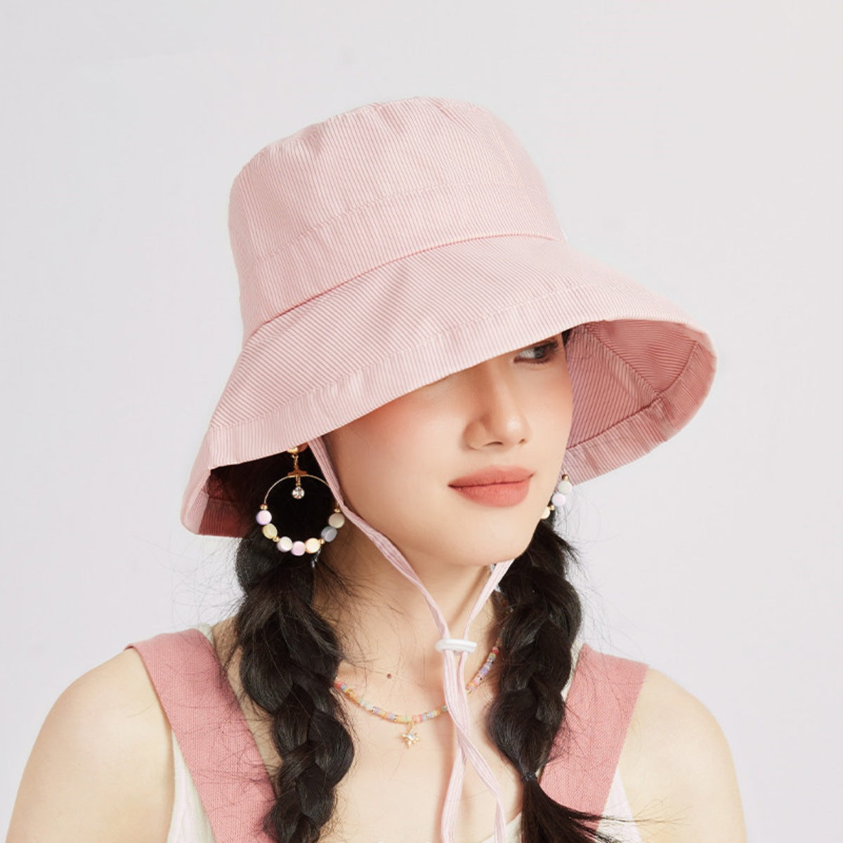Person wearing a pink bucket hat with a white background