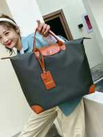 Person holding a large black and orange bag with a visible brand tag.