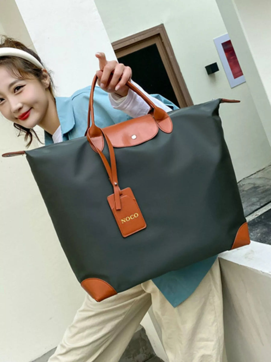 Person holding a large black and orange bag with a visible brand tag.