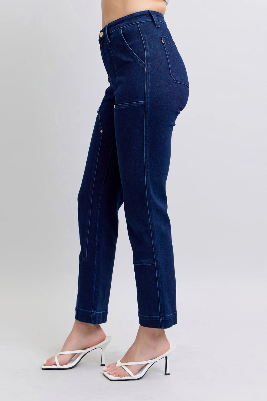 Navy blue jeans worn by a person on a light gray background