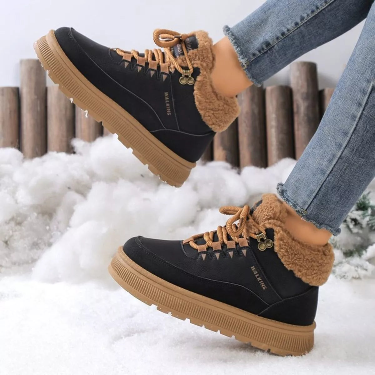 Black winter boots with brown soles and fur lining worn in the snow.