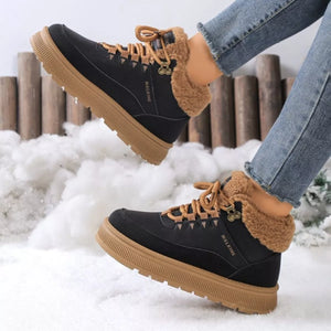 Black winter boots with brown soles and fur lining worn in the snow.