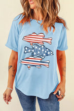 Woman wearing a light blue t-shirt with fish designs featuring the American flag on a beige background