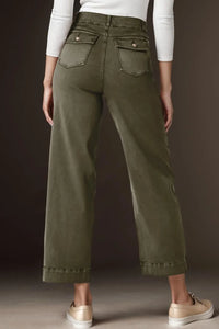 Person wearing olive green pants with a plain background