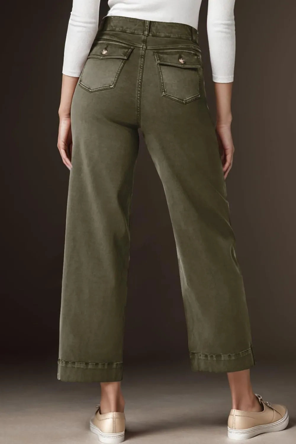 Person wearing olive green pants with a plain background