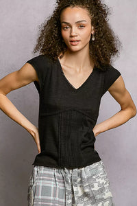 Woman wearing a black sleeveless top with plaid pants against a gray background