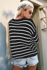 Woman wearing a black and white striped sweater and denim shorts, standing outdoors.
