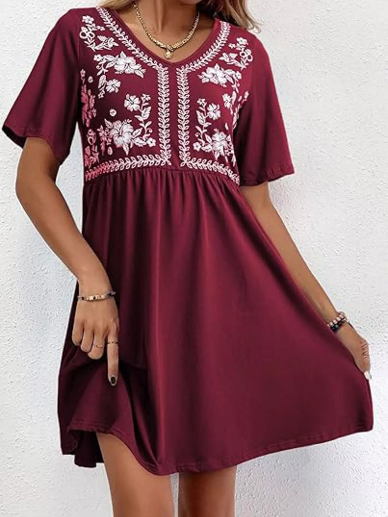 Maroon dress with white floral embroidery on a white background