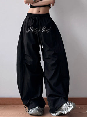 Black wide-leg pants with 'PetiteGirl' branding worn by a person on a plain background