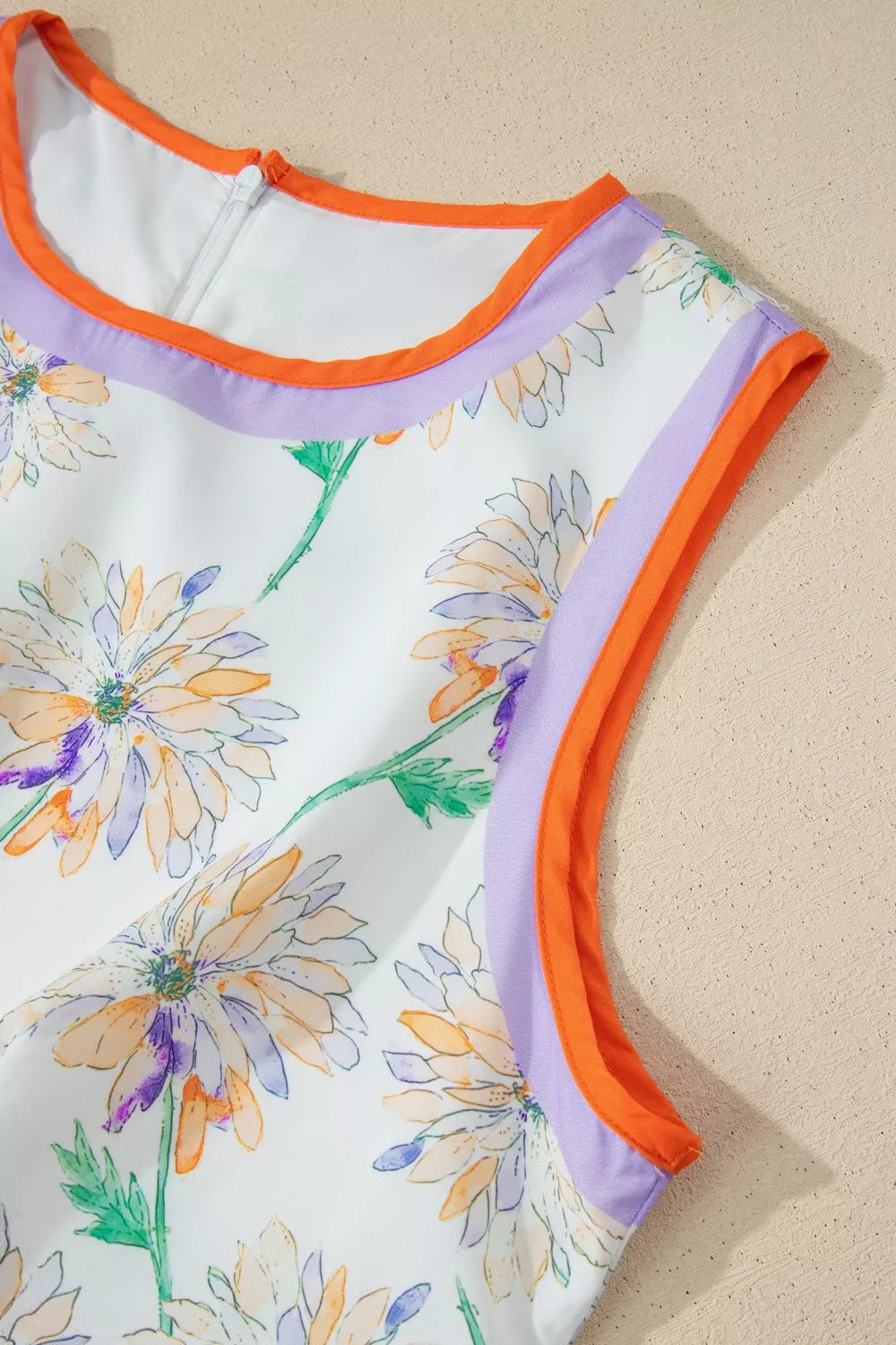 Floral swimsuit with orange trim on a beige background