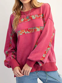Pink sweatshirt with floral patterns on a plain background