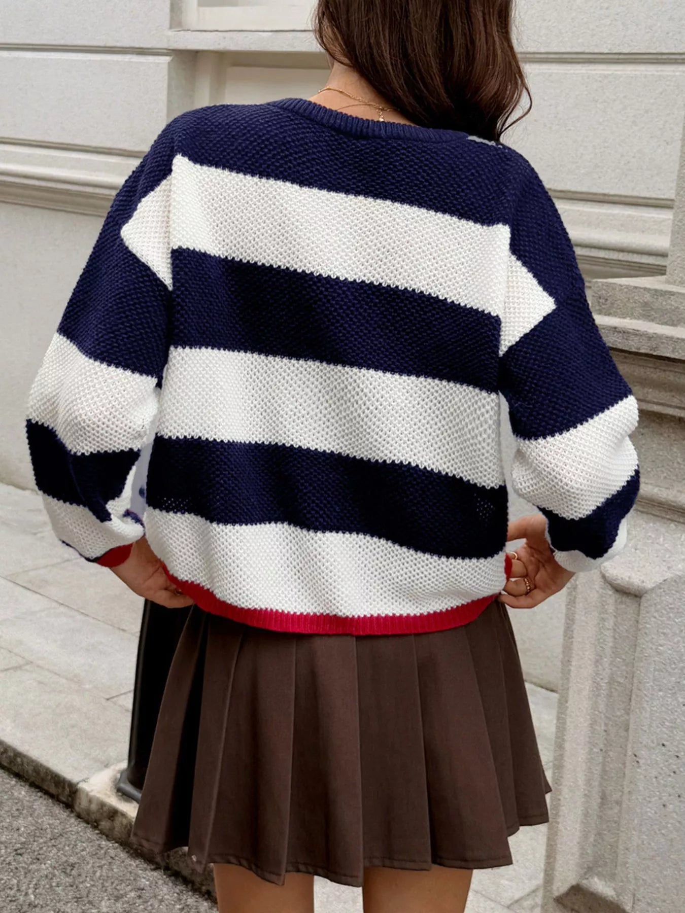 Person wearing a navy and white striped sweater with a brown skirt outdoors.