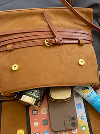 Brown leather bag with items like a phone and wallet spilling out.