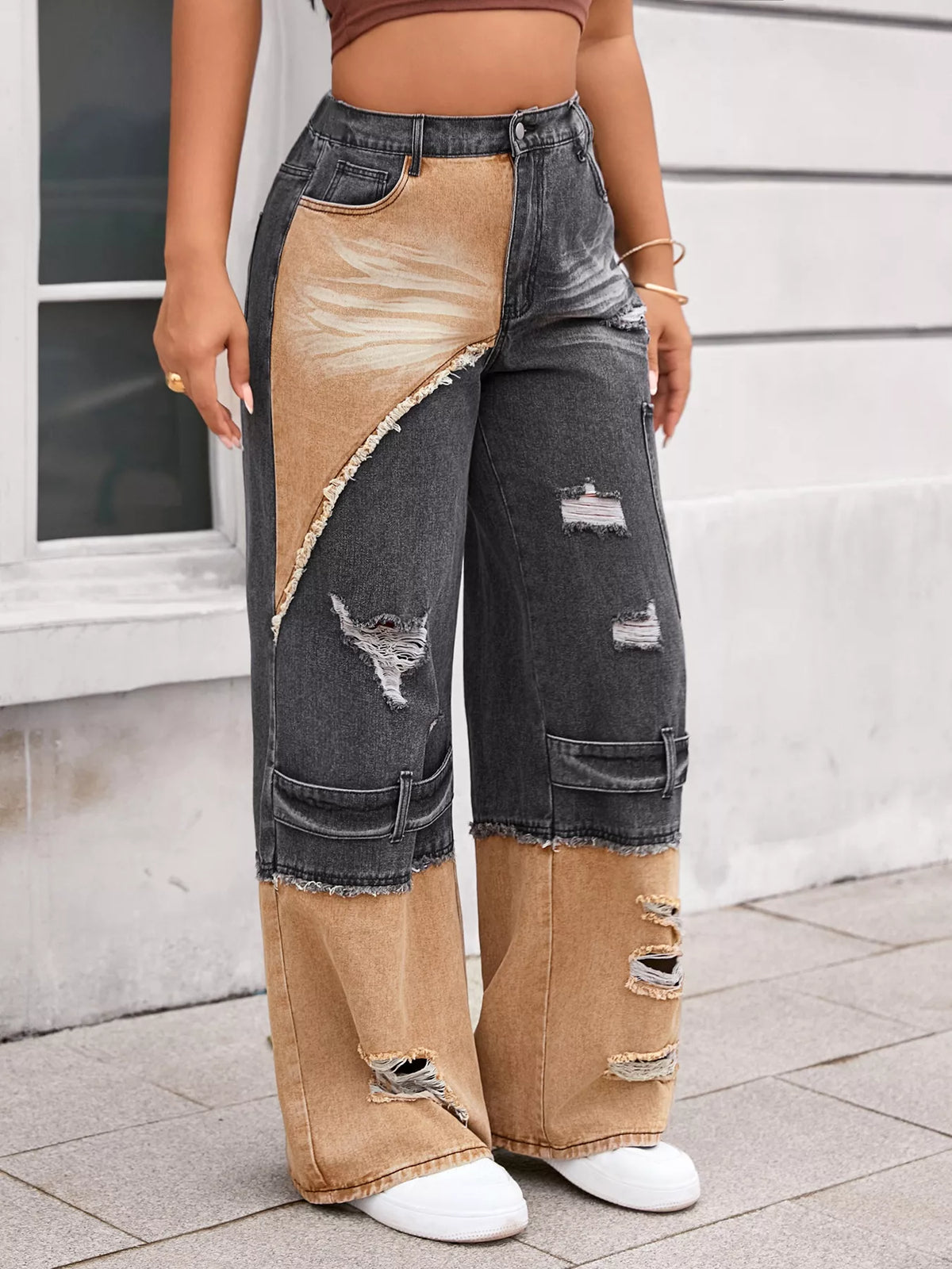 Person wearing patchwork jeans with a neutral background