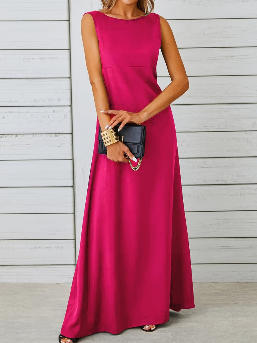 Woman wearing a pink sleeveless dress holding a black clutch against a light wooden panel background