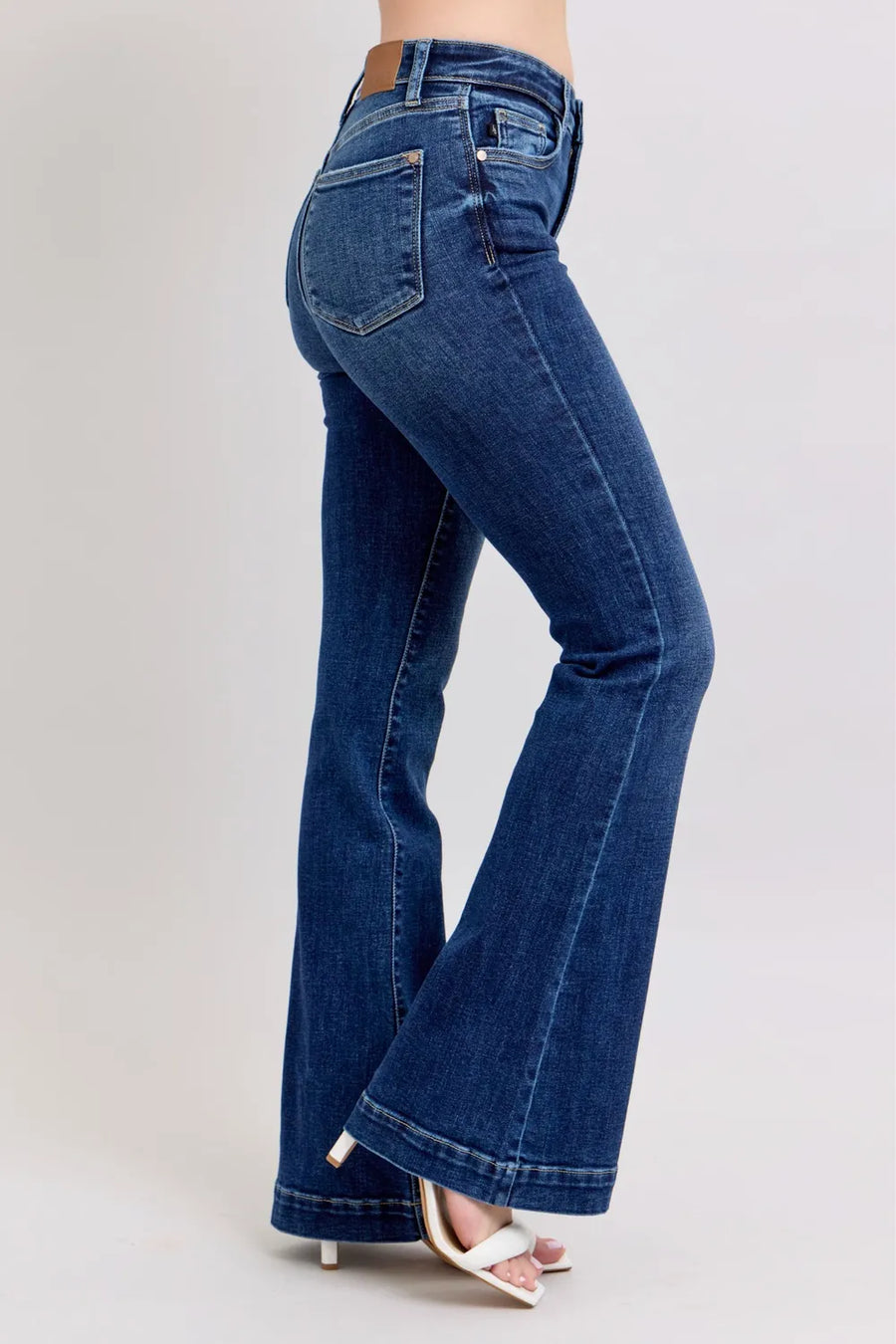 Blue flared jeans worn by a person on a light gray background