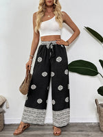Woman wearing a white top and black patterned pants with a white background