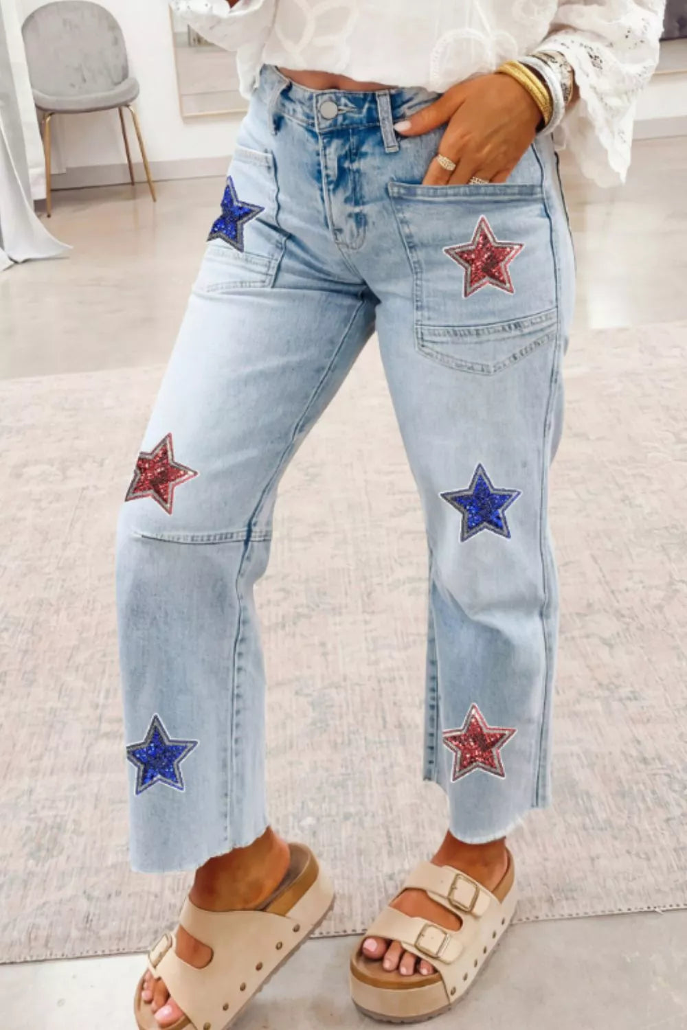 Light blue jeans with star patches worn indoors.