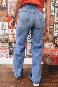 Person wearing blue jeans standing in front of a wall with vintage album covers.