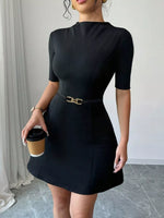 Woman wearing a black dress holding a coffee cup indoors.