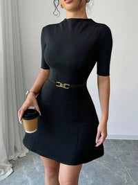 Woman wearing a black dress holding a coffee cup indoors.