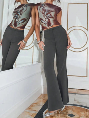 Person wearing a patterned top and dark pants standing in front of a mirror.