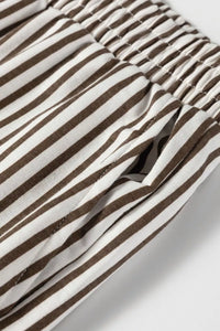 Close-up of brown and white striped fabric with a brand logo.