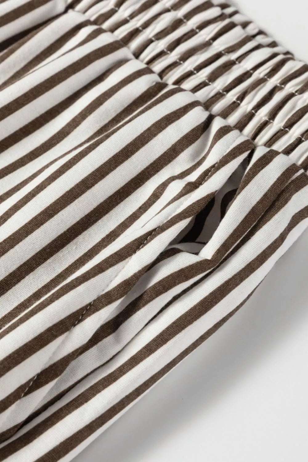 Close-up of brown and white striped fabric with a brand logo.